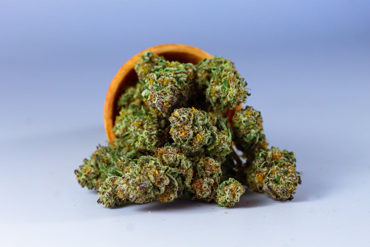 High-quality close-up of cannabis buds in a wooden bowl with a neutral background.